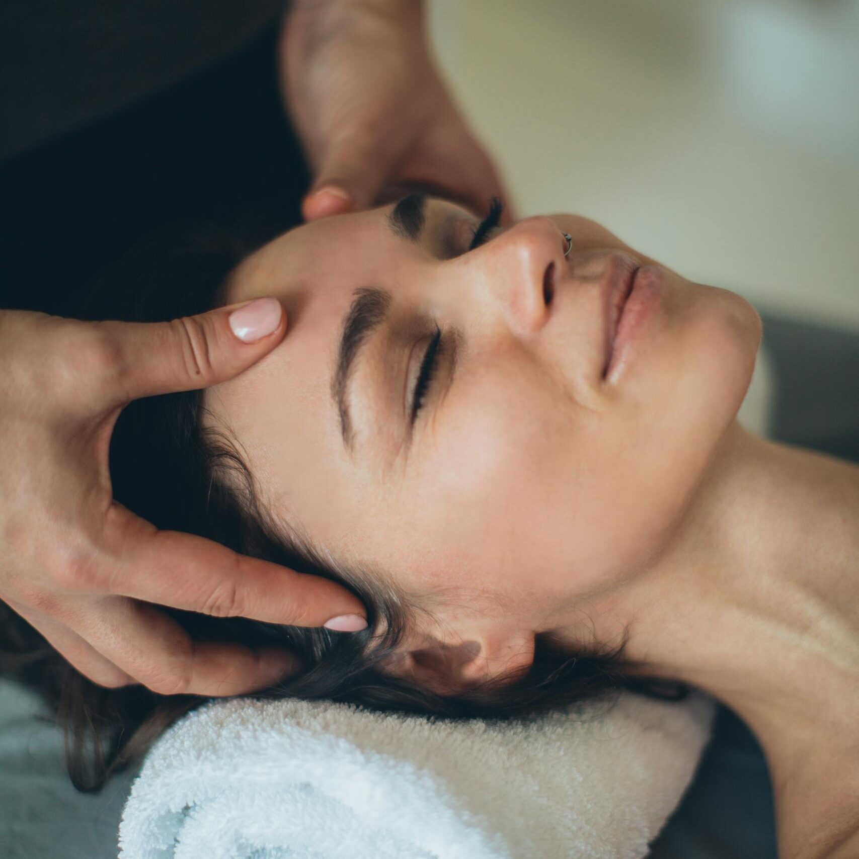 Woman enjoying a soothing facial massage at a spa, eyes closed and relaxed.